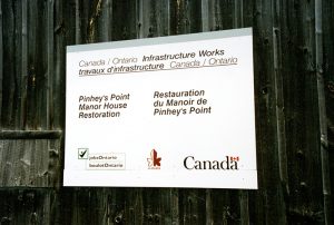 Colour photo of 1995–1996 Canada/Ontario Infrastructure Works sign which reads "Pinhey's Point Manor House Restoration" with jobsOntario, Kanata and Canada logos (PPF Collection)