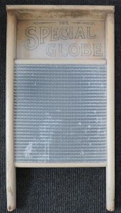 A colour photo of a well-worn wood and metal washboard, trademarked "The Special Globe" made by E.B. Eddy Co. of Hull, Quebec, for scrubbing clothes clean before washing machines came into use. "The Special Globe" (PPF Collections, Gift of Betty Ann Koene)