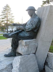 A colour photo of the moving sculpture by Ron Cowle of Lanark of a sitting soldier reading a letter from home, part of the impressive West Carleton War Memorial site in Carp designed by South March architect Malcolm Wildeboer. (B.E.)